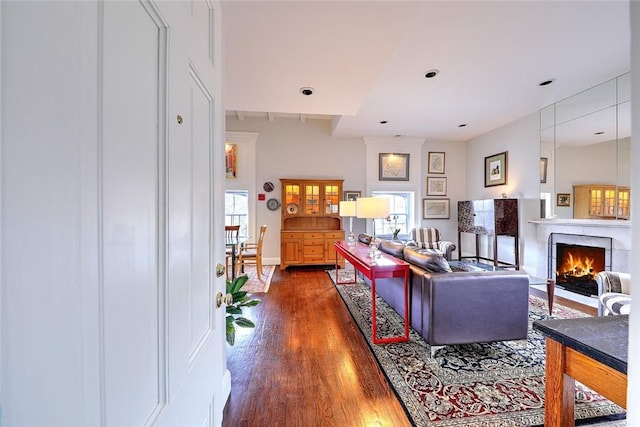 living room with dark wood finished floors and a lit fireplace