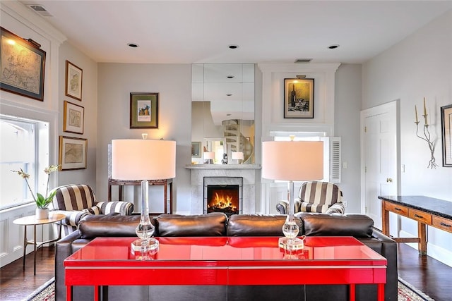 living area featuring a large fireplace, visible vents, and dark wood-type flooring