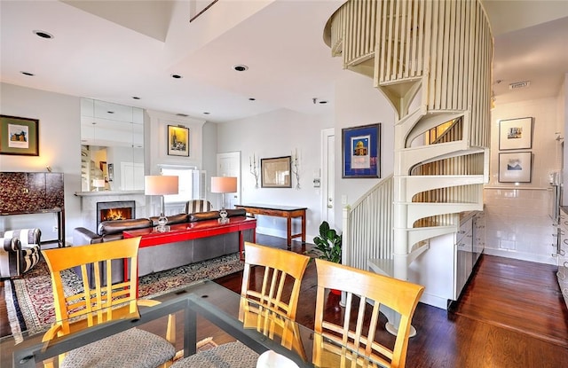 dining area featuring a lit fireplace, dark wood-style flooring, and recessed lighting