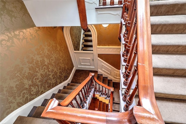 stairway with baseboards and wallpapered walls