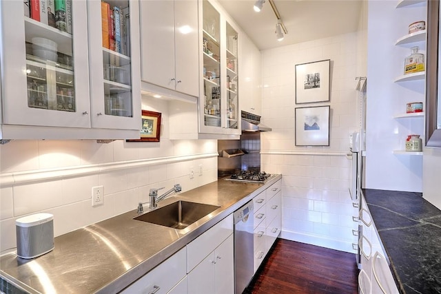 kitchen with glass insert cabinets, stainless steel countertops, white cabinetry, and a sink