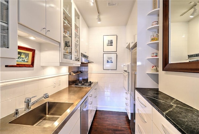 kitchen with glass insert cabinets, a sink, under cabinet range hood, and open shelves