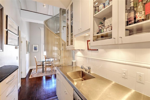 kitchen featuring dark wood finished floors, stainless steel countertops, glass insert cabinets, white cabinets, and a sink