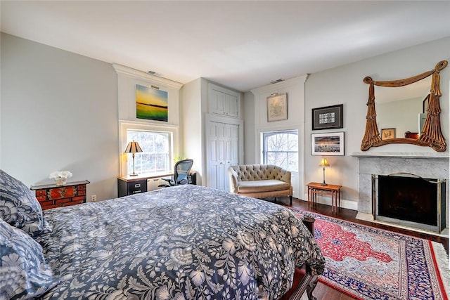 bedroom featuring a closet, a premium fireplace, visible vents, and wood finished floors