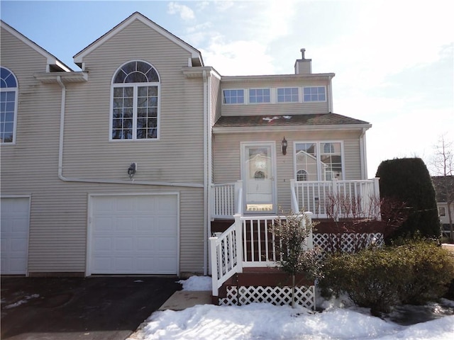 view of front of property featuring a garage, a porch, a chimney, and stairs