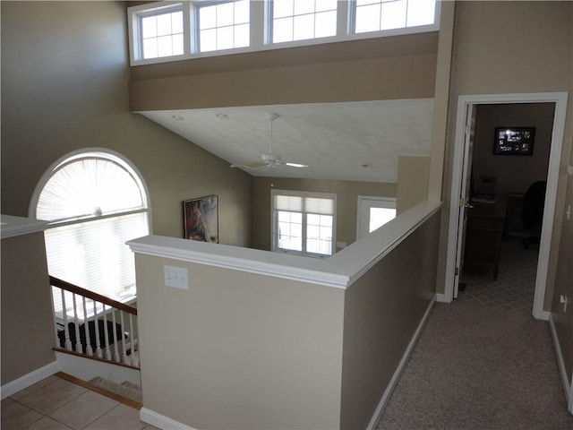 hall with a wealth of natural light, baseboards, and a high ceiling