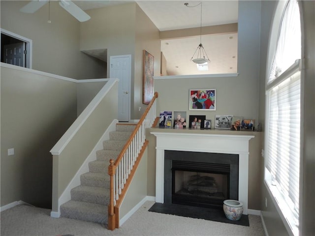 interior space with a fireplace with flush hearth, carpet flooring, ceiling fan, and baseboards