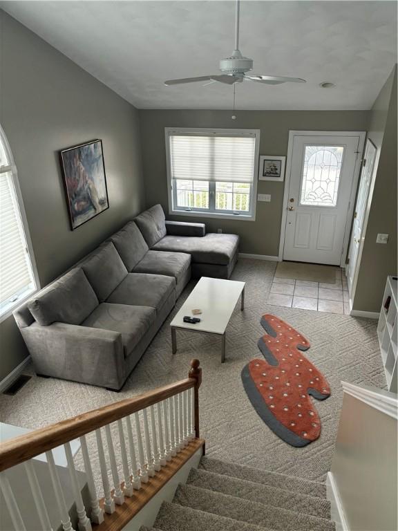 living room with stairs, light tile patterned floors, visible vents, and baseboards