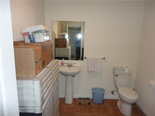 half bath featuring baseboards, a sink, toilet, and tile patterned floors