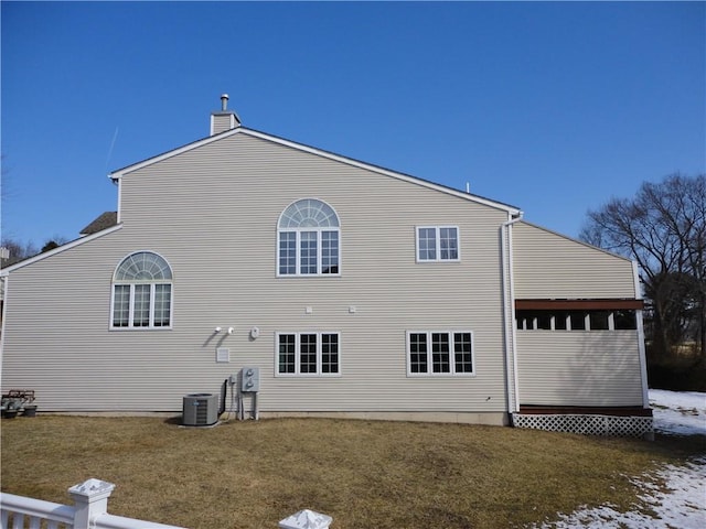 rear view of house with a lawn, a chimney, and central air condition unit