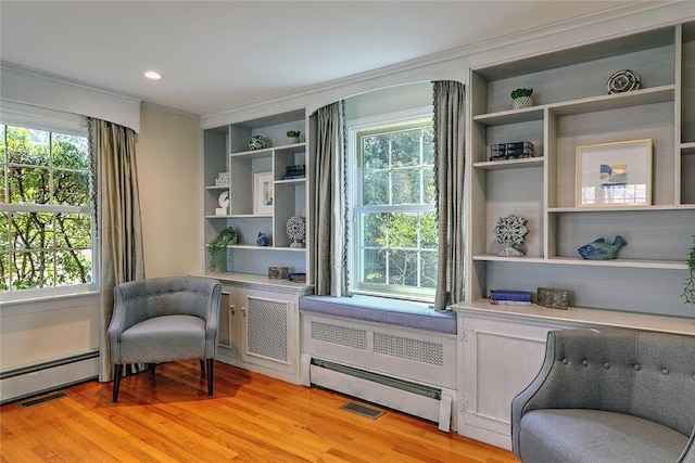 sitting room with a baseboard heating unit, light wood-style flooring, and a healthy amount of sunlight