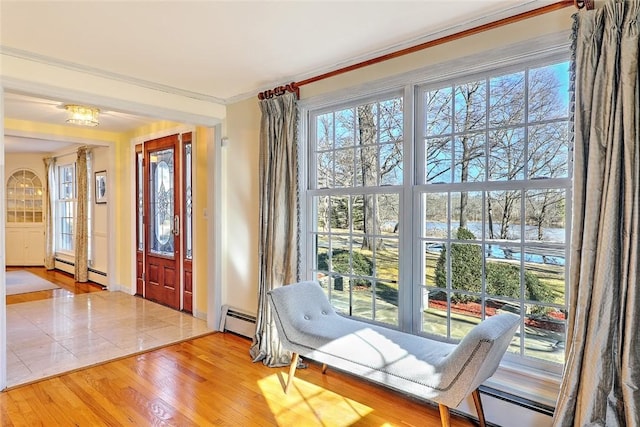 interior space with baseboards, a baseboard radiator, ornamental molding, and wood finished floors