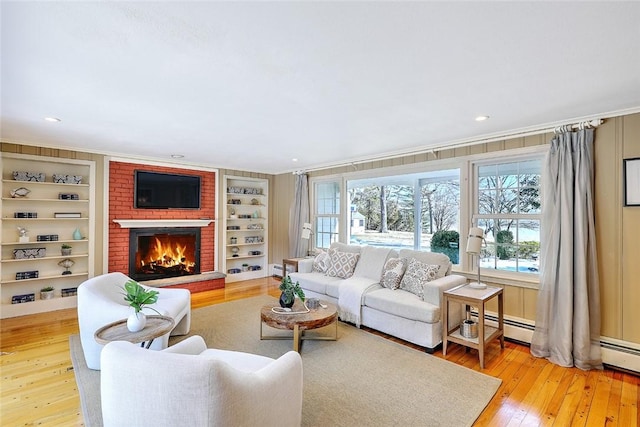 living area featuring a brick fireplace, wood-type flooring, built in features, and crown molding