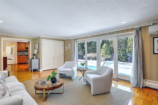 living room with ornamental molding, baseboard heating, and light wood-style flooring