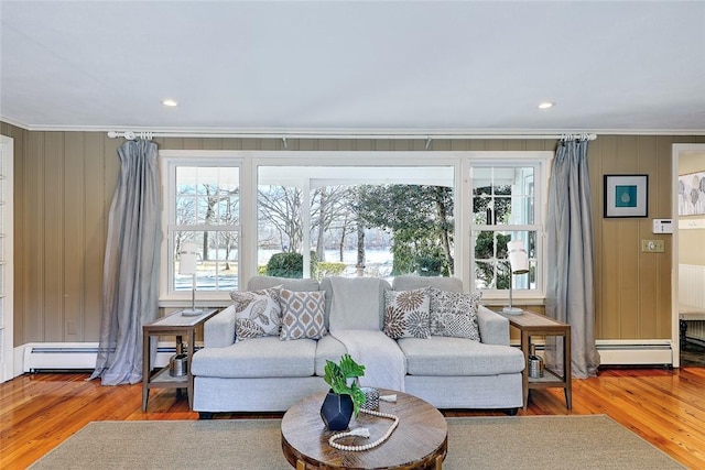 living area with ornamental molding, a baseboard radiator, baseboard heating, and wood finished floors