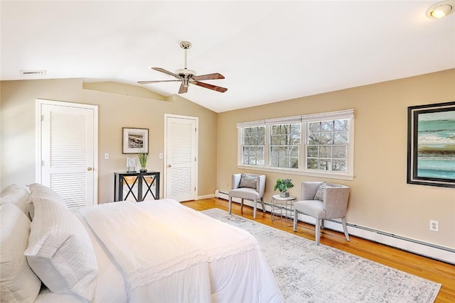 bedroom with light wood finished floors, visible vents, lofted ceiling, ceiling fan, and multiple closets