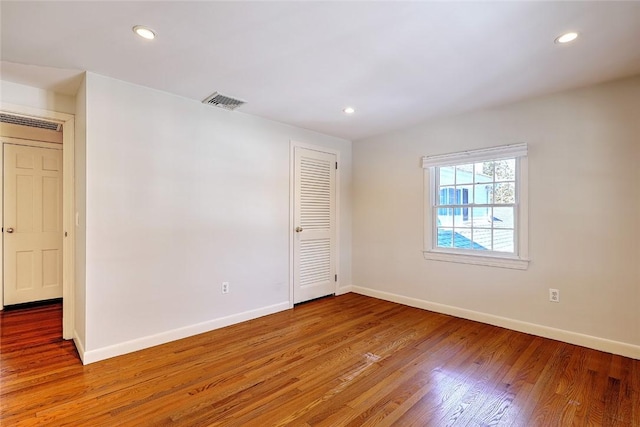 spare room with recessed lighting, visible vents, baseboards, and wood finished floors