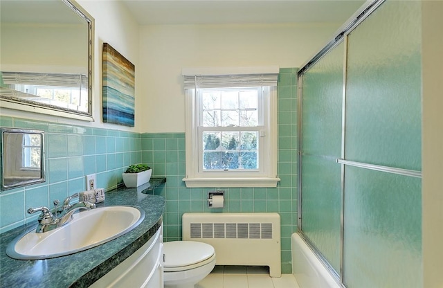 full bath featuring toilet, tile walls, radiator heating unit, and tile patterned floors