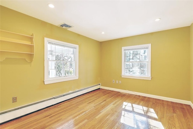 unfurnished room featuring plenty of natural light, baseboards, baseboard heating, and light wood-style flooring