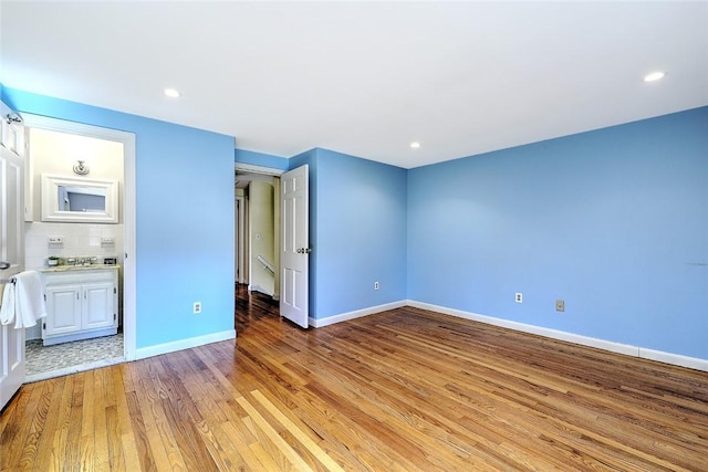 unfurnished bedroom with recessed lighting, baseboards, ensuite bath, and light wood finished floors