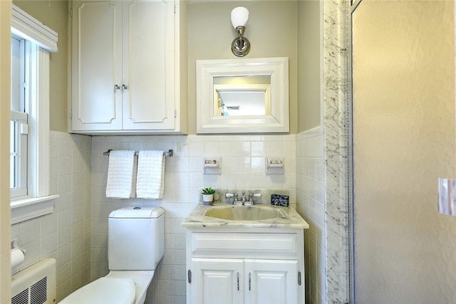 bathroom featuring vanity, toilet, and tile walls