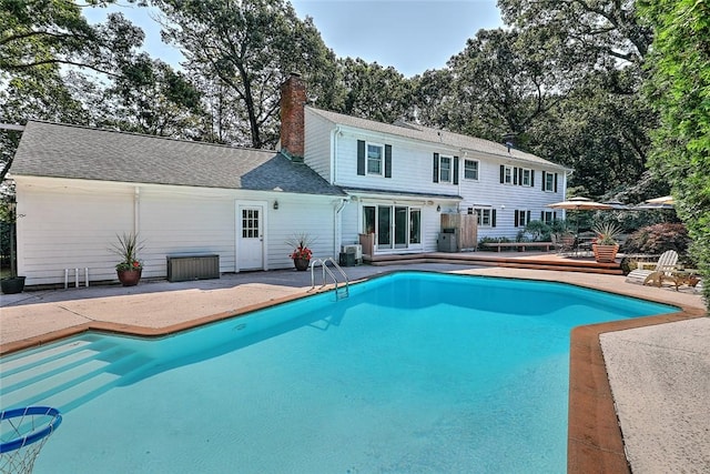 rear view of house featuring a deck, central AC, an outdoor pool, a chimney, and a patio area