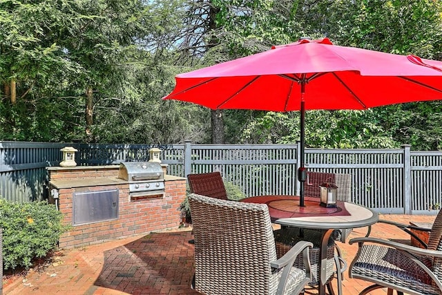 view of patio featuring outdoor dining space, exterior kitchen, grilling area, and fence