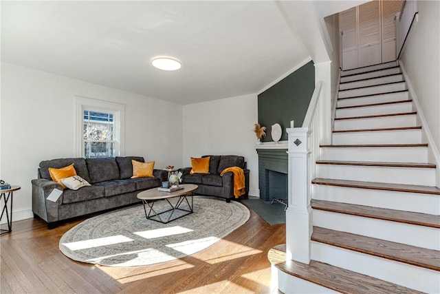 living room with a fireplace with flush hearth, hardwood / wood-style flooring, baseboards, and stairs