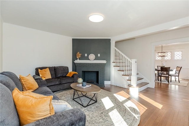 living area featuring stairs, a fireplace, wood finished floors, and baseboards