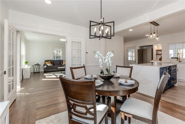 dining area with light wood-style flooring, a notable chandelier, and recessed lighting