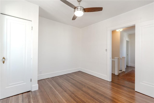 spare room featuring ceiling fan, baseboards, and wood finished floors