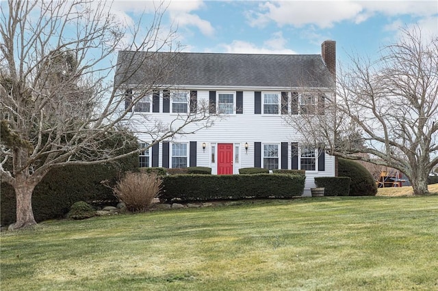 colonial-style house with a chimney and a front yard