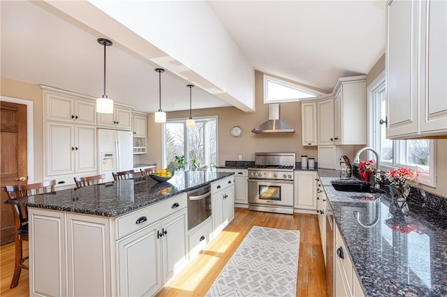 kitchen with a warming drawer, high end stainless steel range, a sink, white fridge with ice dispenser, and wall chimney exhaust hood