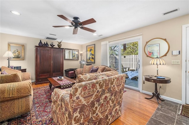 living area with light wood-type flooring, visible vents, ceiling fan, and baseboards