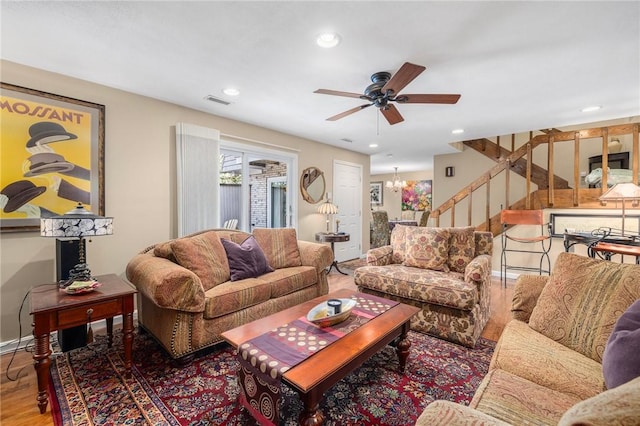 living area featuring recessed lighting, stairway, wood finished floors, baseboards, and ceiling fan with notable chandelier