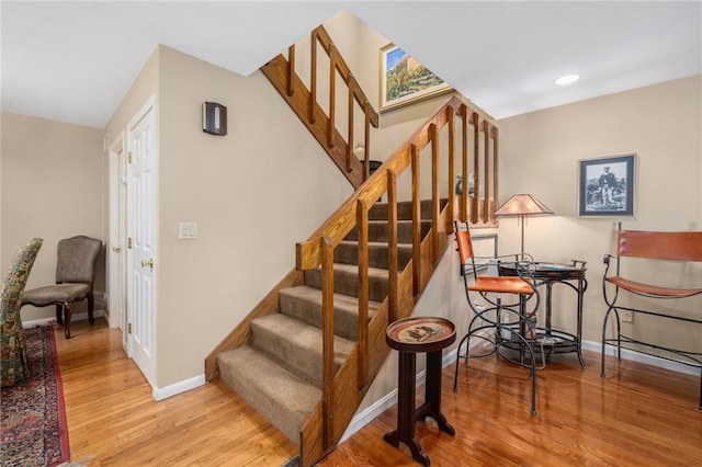 stairs with recessed lighting, wood finished floors, and baseboards