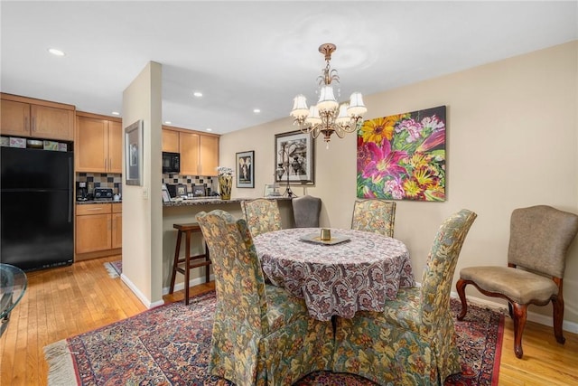 dining room featuring light wood finished floors, recessed lighting, baseboards, and an inviting chandelier