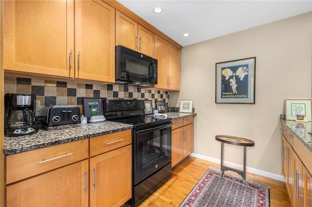 kitchen with dark stone countertops, light wood-style floors, backsplash, and black appliances