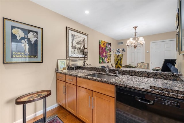 kitchen with a sink, visible vents, light wood-style floors, dishwasher, and dark stone countertops