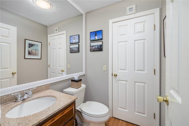 bathroom with vanity, toilet, and wood finished floors