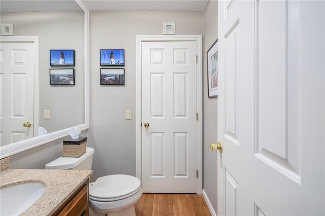 half bath featuring vanity, toilet, and wood finished floors