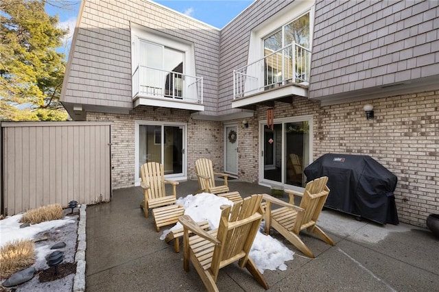 view of patio with area for grilling, fence, and a balcony