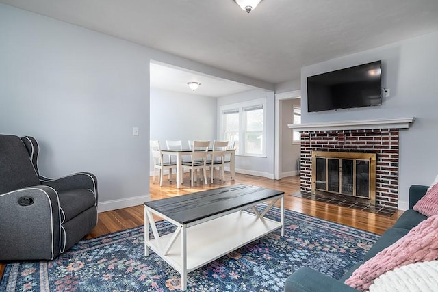 living room featuring a fireplace, baseboards, and wood finished floors