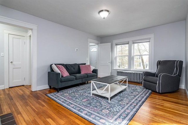 living area with radiator heating unit, baseboards, and hardwood / wood-style floors