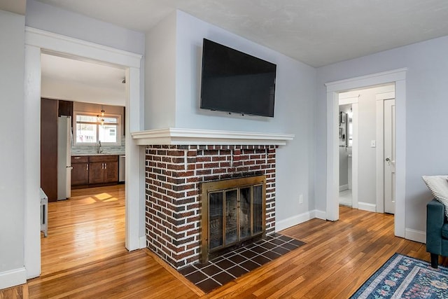 living room featuring a fireplace, baseboards, and hardwood / wood-style floors