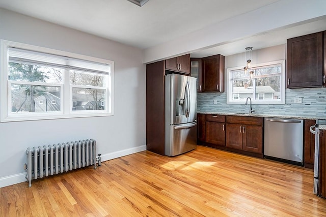 kitchen featuring radiator, tasteful backsplash, appliances with stainless steel finishes, and hanging light fixtures