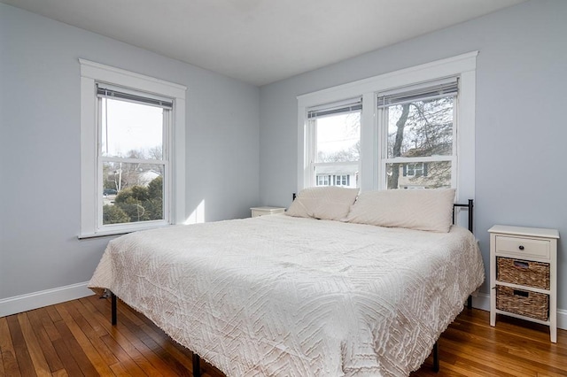 bedroom with multiple windows, baseboards, and dark wood finished floors