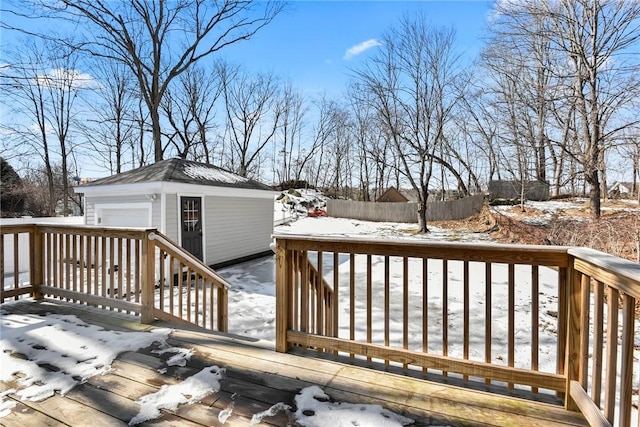 snow covered deck with an outbuilding, fence, and a garage