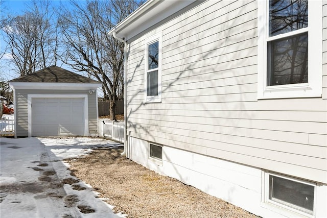 view of property exterior featuring a garage, driveway, fence, and an outbuilding