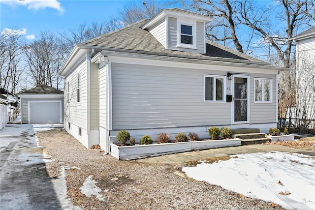 view of front facade with an outbuilding, roof with shingles, driveway, and entry steps